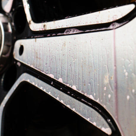 Close-up of a car wheel with primo wheel cleaner reacting with iron fallout