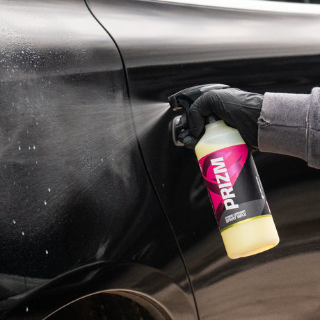 Person squirting Prizm car care product to a black car